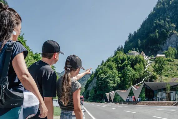 Familie blickt auf Rutsche zum Schloss in alpiner Landschaft